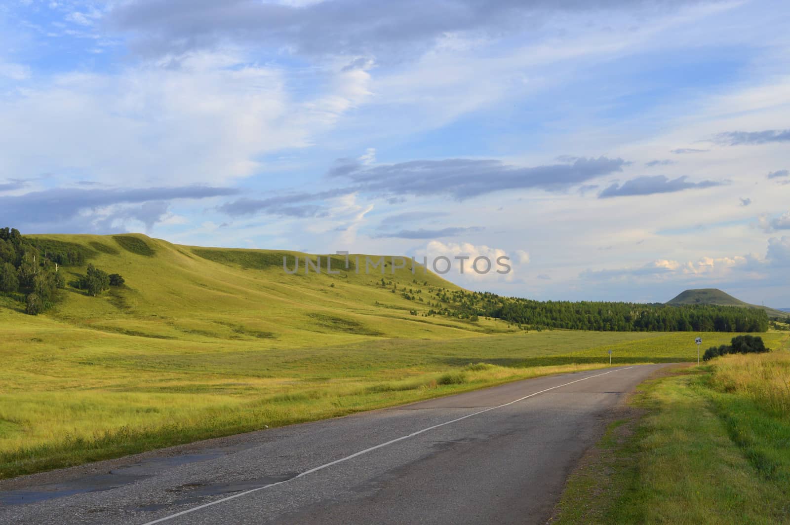 summer landscape with road, mountain and blue sky with clouds