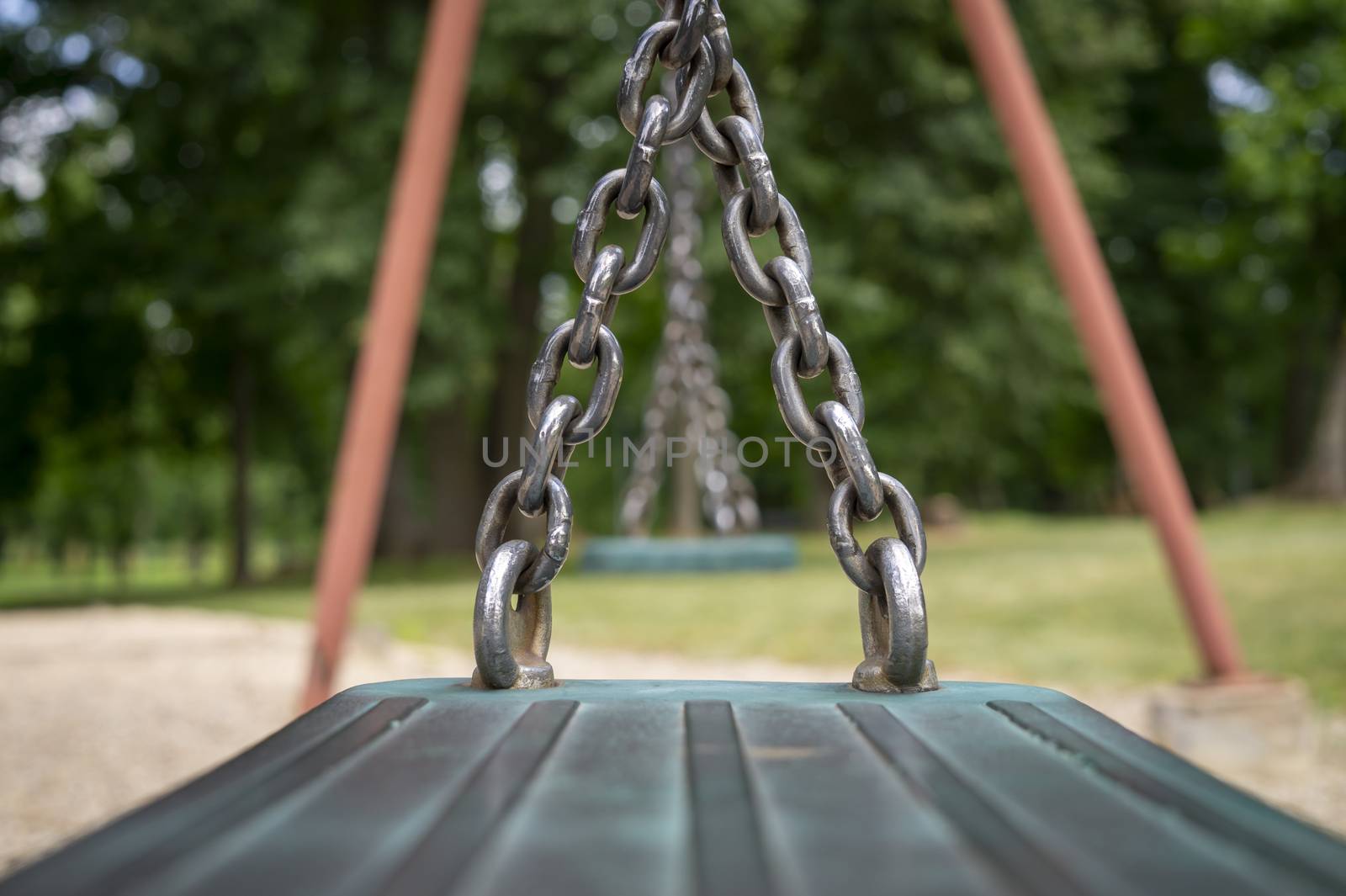 Close up detail of the chain attached to the seat on a playground swing in a low angle view