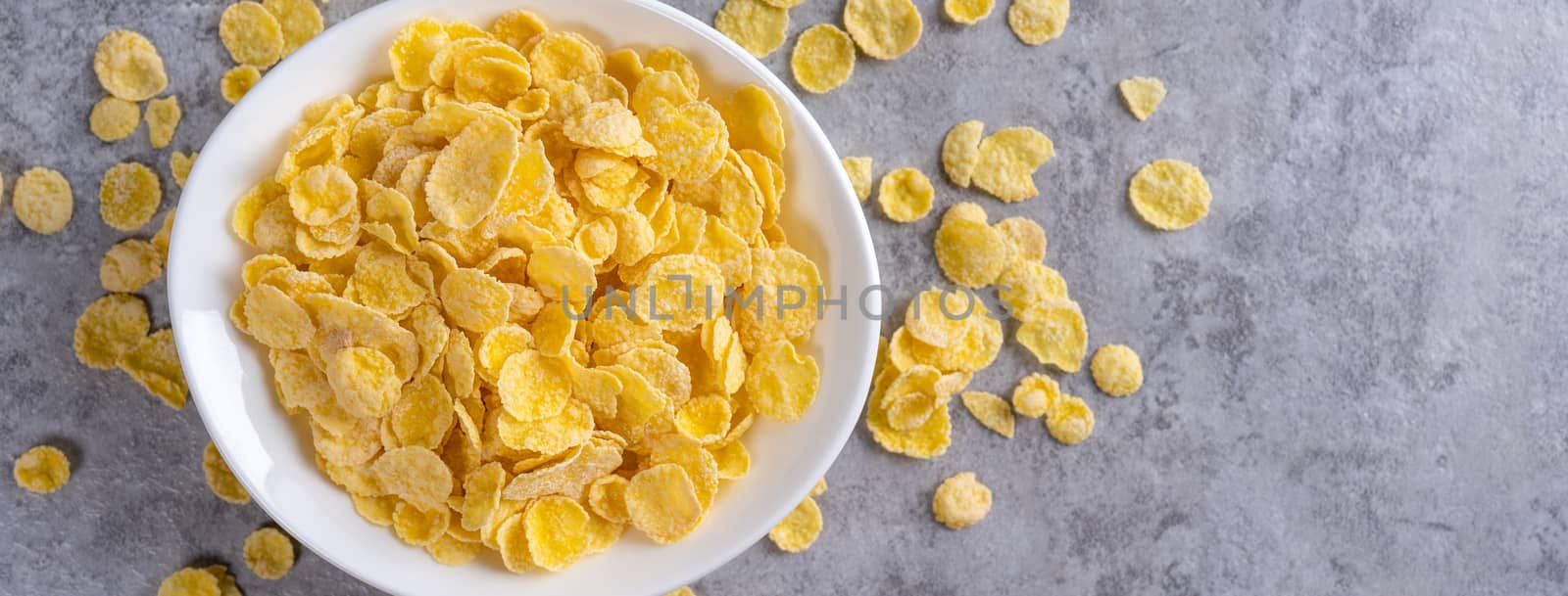 Corn flakes bowl sweets on gray cement background, top view flat lay layout design, fresh and healthy breakfast concept.