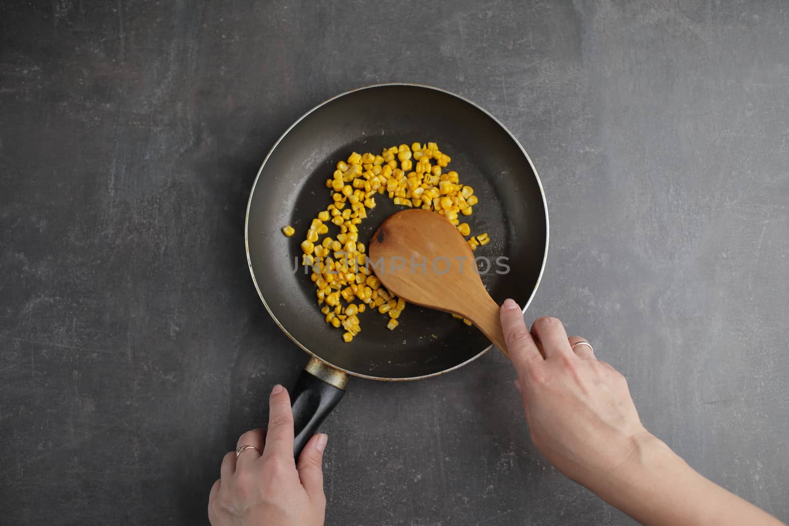 Diet. Organic Grilled Corn in a frying pan. Organic farm vegetables. Gray background Top view. Wooden spoon in hand. Environmentally friendly products