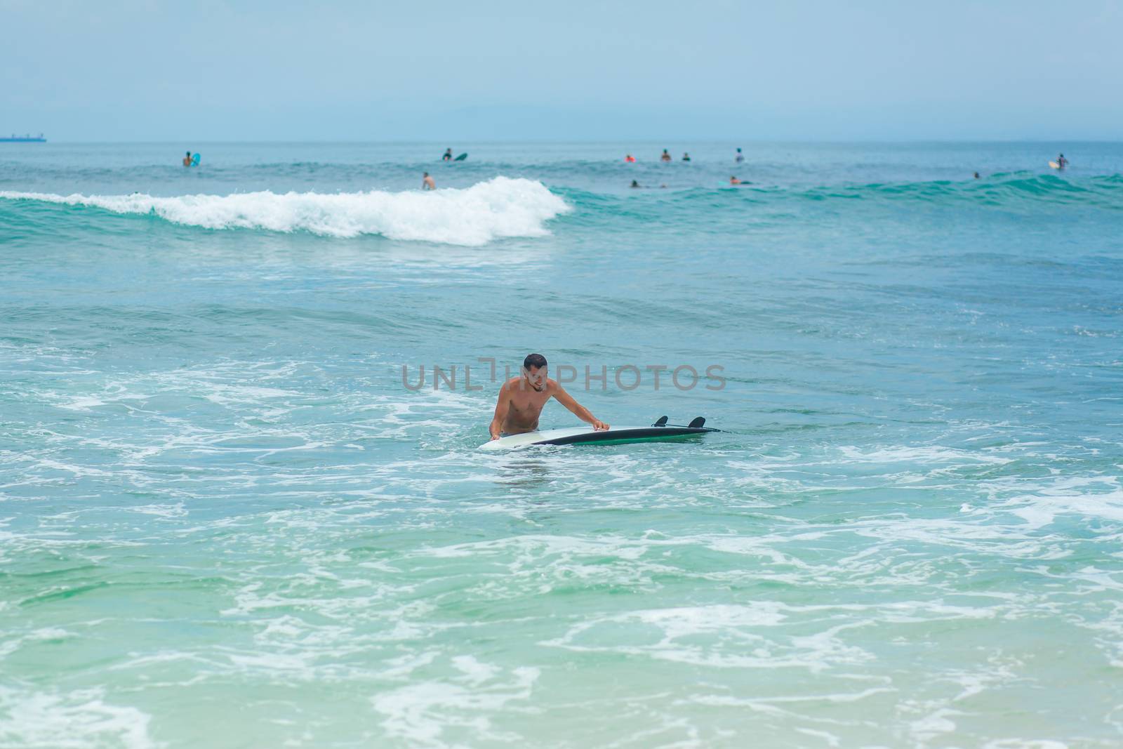 The guy is swimming on the surf board on the ocean. Healthy active lifestyle in summer vocation