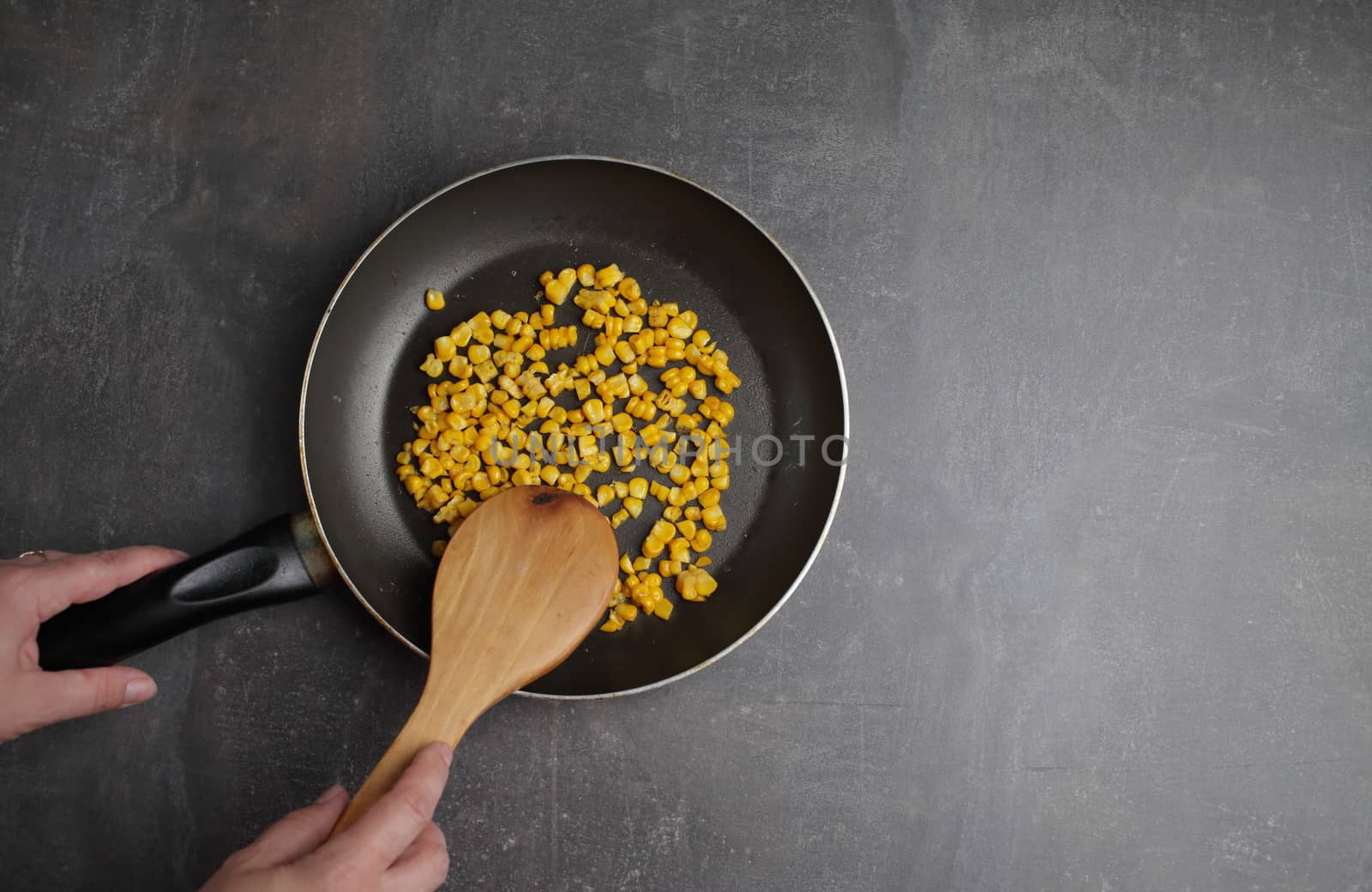 Diet. Organic Grilled Corn in a frying pan. Organic farm vegetables. Gray background Top view. Wooden spoon in hand. Environmentally friendly products
