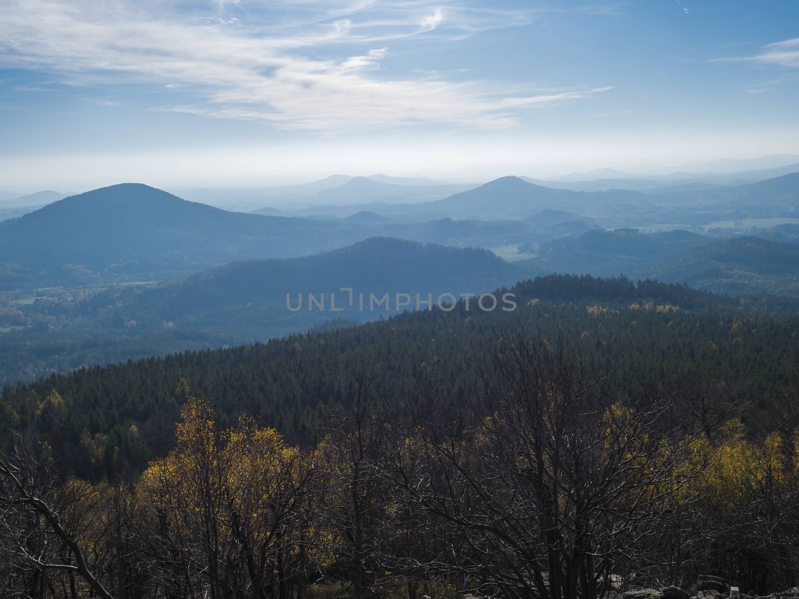 Luzicke hory panorama, view from Hochwald Hvozd, the most attractive view-points of the Lusatian Mountains with autumn colored deciduous and coniferous tree forest and green hills, golden hour light.