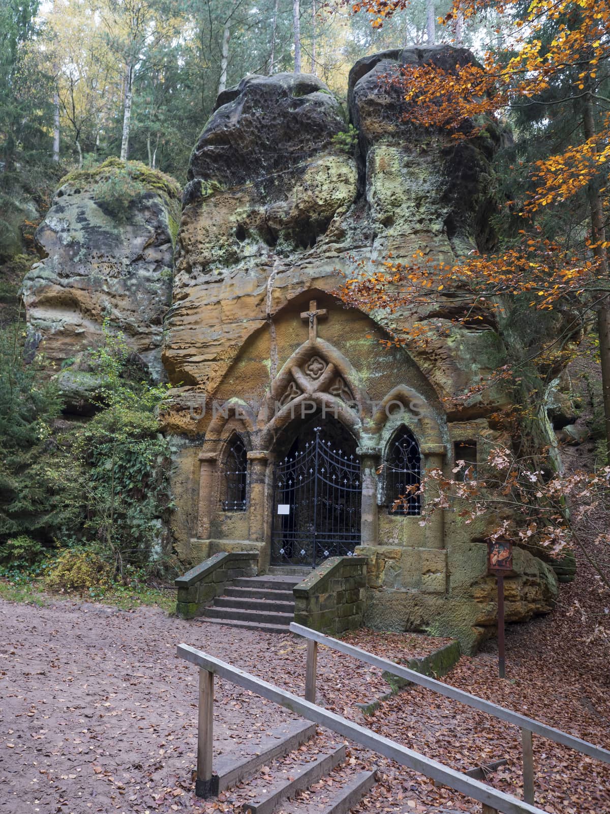 Ancient chapel carved in sandstone rock Modlivy Dul dedicated to the Virgin Mary of Lourdes in beautiful autumn forest near village Sloup v Cechach, Czech Republic.