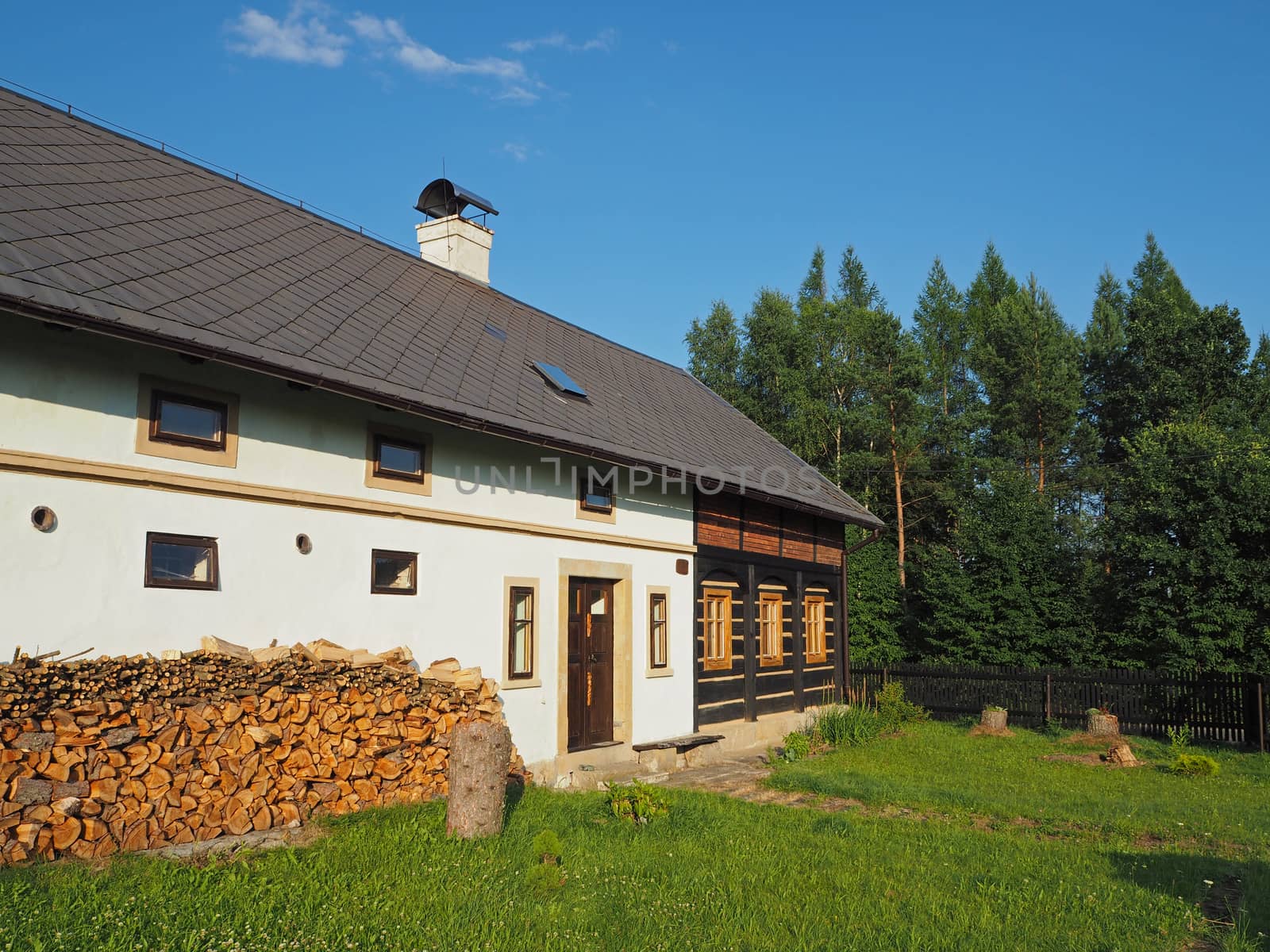 half timbered masonry old rustic house with chopped wood and green grass