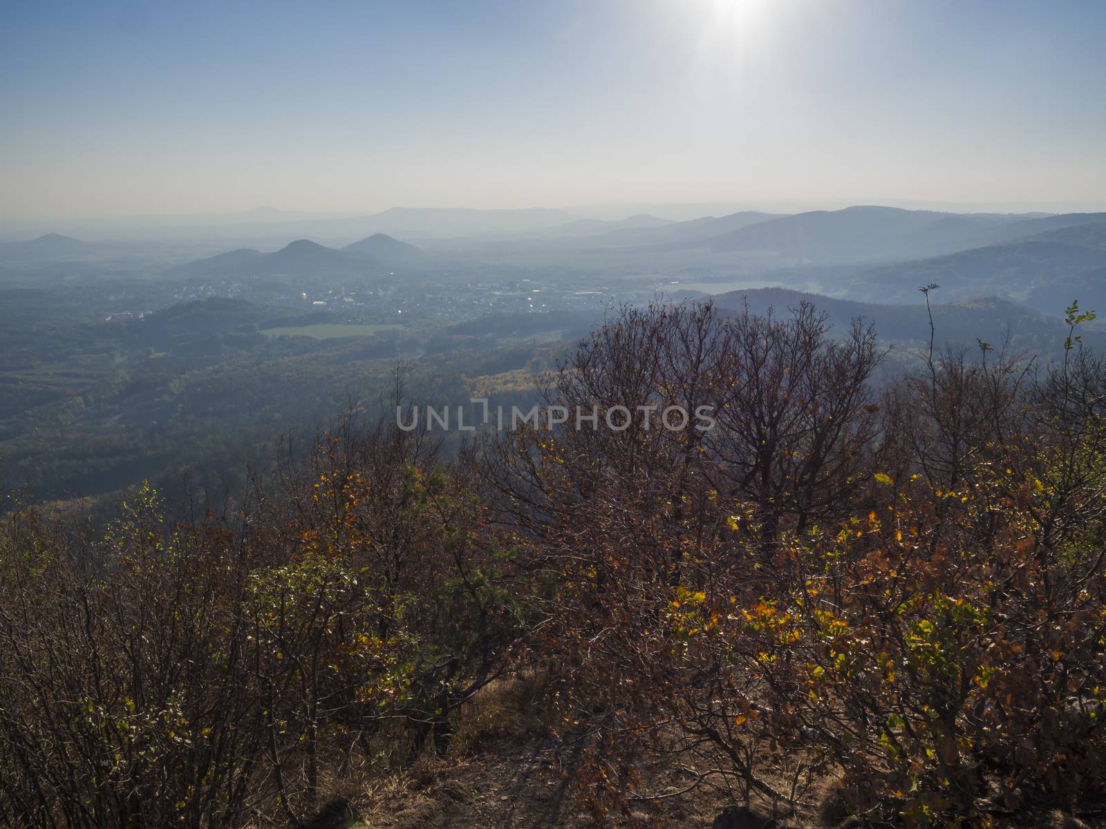 Lusatian Mountains or luzicke hory, view from Klic or Kleis one of the most attractive view-points of the Lusatian Mountains with autumn colored deciduous and coniferous tree forest and green hills, golden hour light.