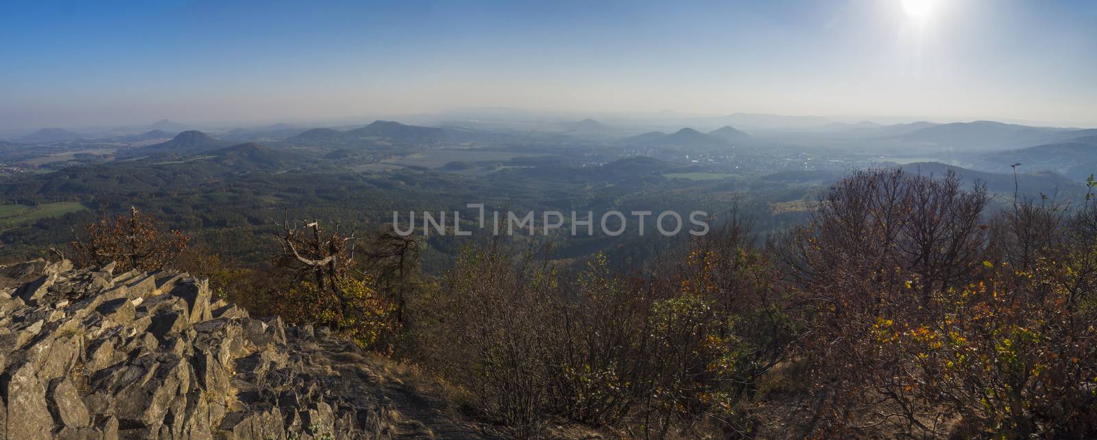 Lusatian Mountains or luzicke hory wide panorama, panoramic view from Klic or Kleis one of the most attractive view-points of the Lusatian Mountains with autumn colored deciduous and coniferous tree forest and green hills, golden hour light.