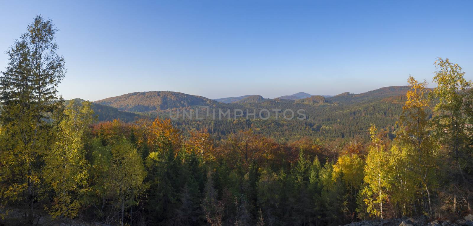 Lusatian Mountains or luzicke hory wide panorama, panoramic view from Klic or Kleis one of the most attractive view-points of the Lusatian Mountains with autumn colored deciduous and coniferous tree forest and green hills, golden hour light.