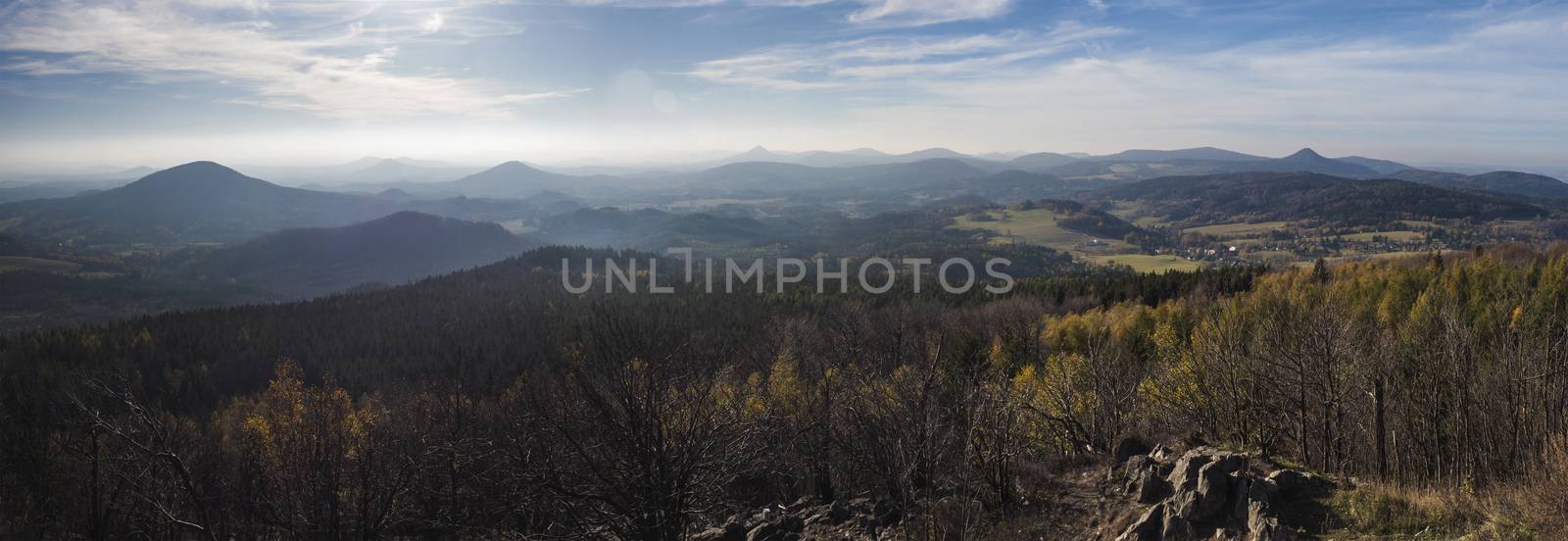 Luzicke hory wide panorama, panoramic view from Hochwald Hvozd one of the most attractive view-points of the Lusatian Mountains with autumn colored deciduous and coniferous tree forest and green hills, golden hour light.