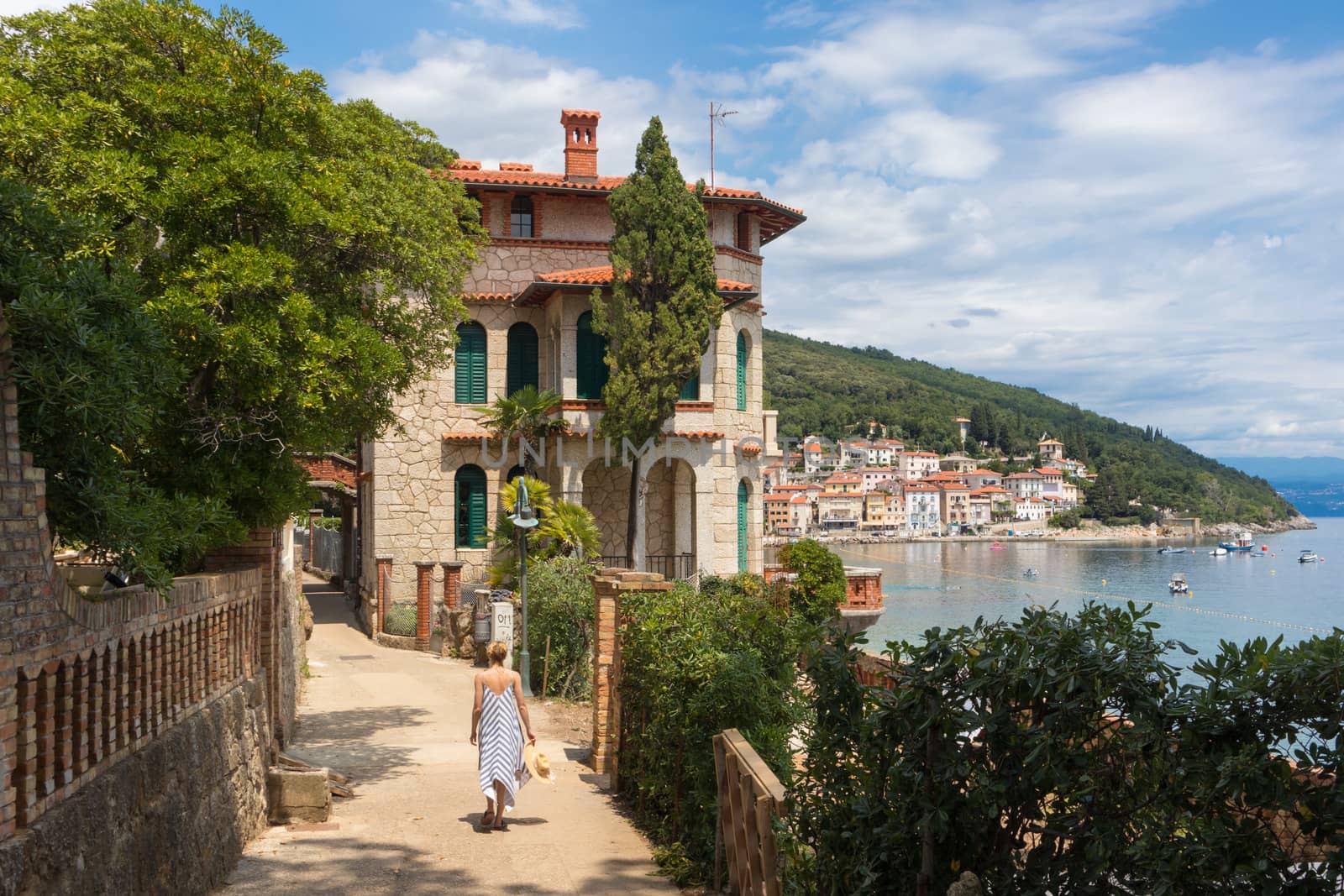 Female tourist walking along Adriatic sea coast relaxing on vacation in Moscenicka Draga, Istria, Croatia. by kasto