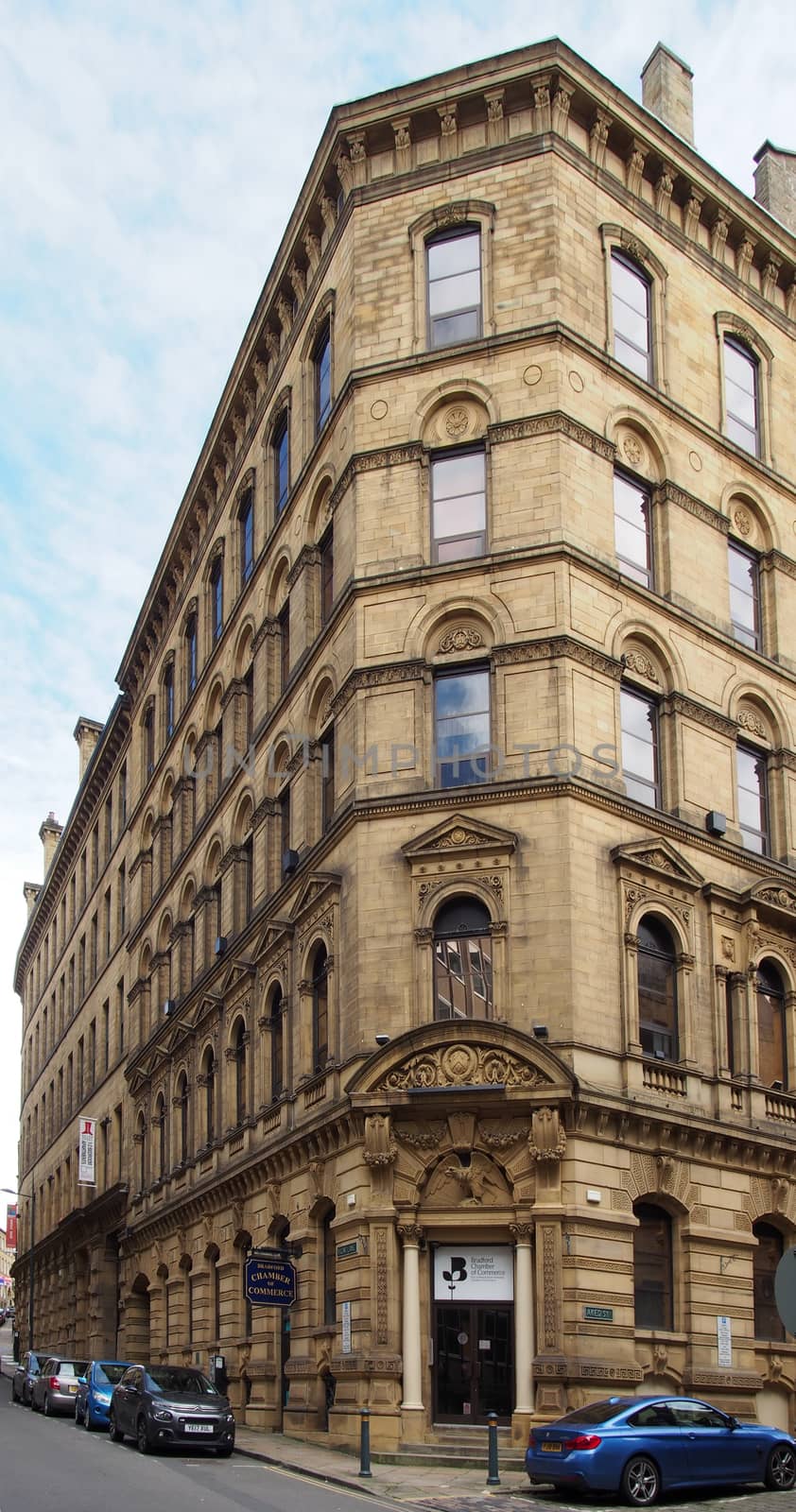 bradford, west yorkshire, united kingdom - 6 july 2019: a tall stone 19th century commercial building in the little germany area of bradford west yorkshire with cars parked along the road