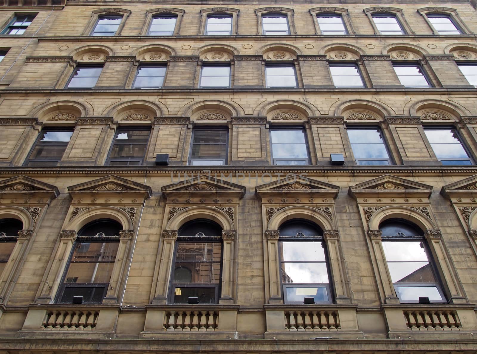 the facade of a large stone 19th century commercial building in the little germany area of bradford west yorkshire with ornate neo classical style windows