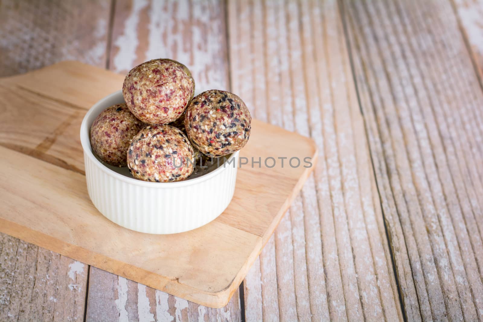 Healthy snack. Energy ball with date plam, black and white sesame, chia and rasin in ceramic bowl on wooden table. Vegan vegetarian.