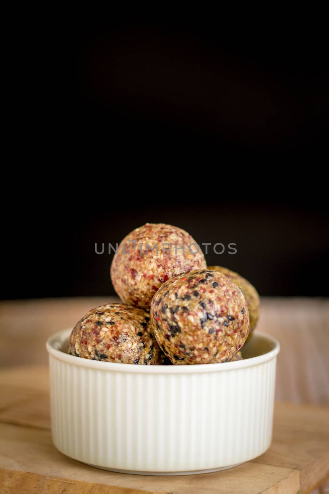 Healthy snack. Energy ball with date plam, black and white sesame, chia and rasin in ceramic bowl on wooden table. Vegan vegetarian.