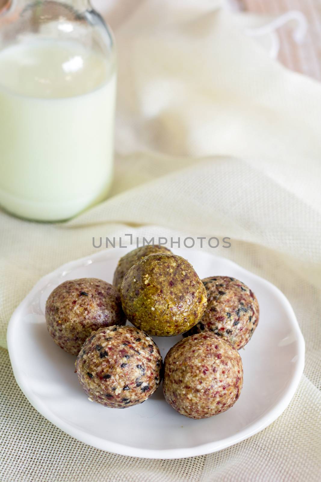 Healthy snack. Energy ball with date plam, black and white sesame, chia and rasin in ceramic palte on table. Vegan vegetarian.