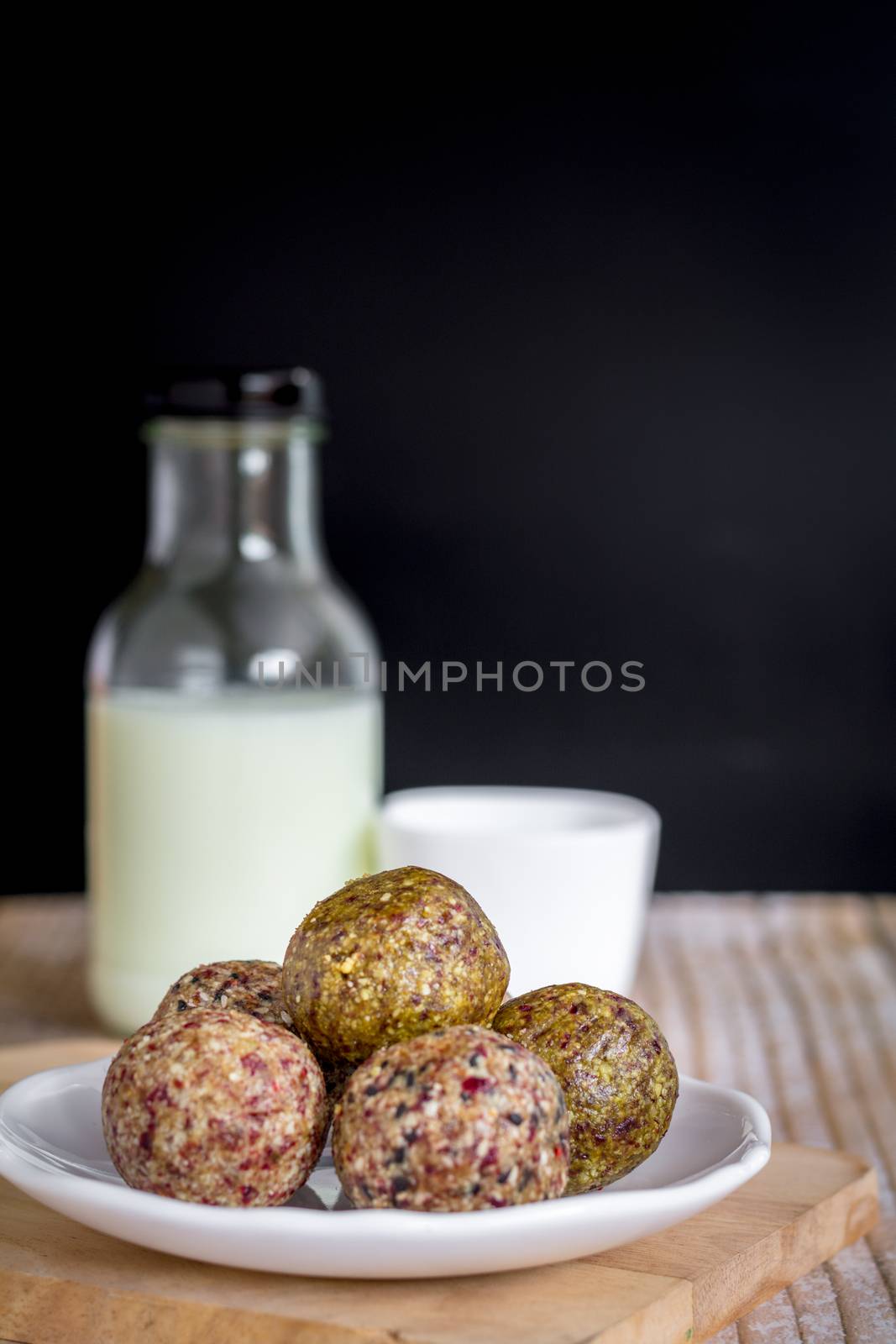 Healthy snack. Energy ball with date plam, black and white sesame, chia and rasin in ceramic palte on table. Vegan vegetarian.