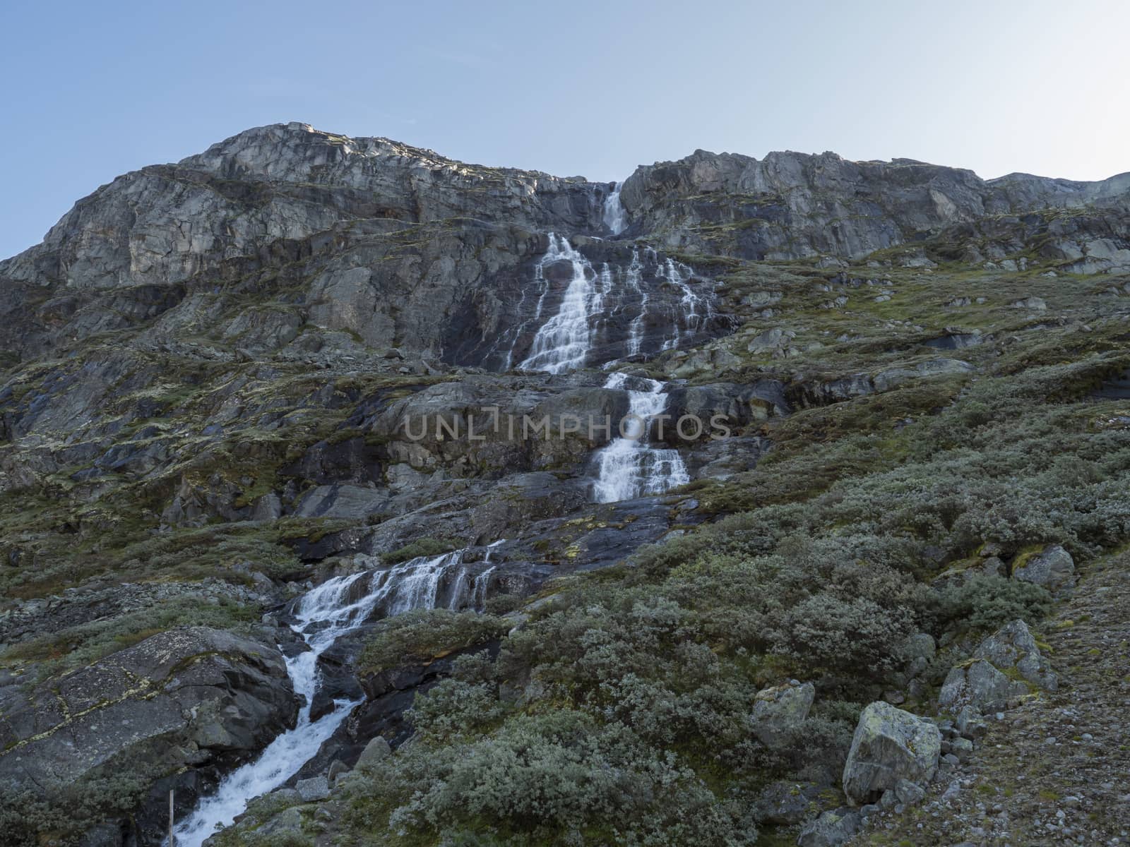 Waterfall in mountains. National tourist scenic route 55 Sognefjellet between Lom and Gaupne, Norway. Blue sky background