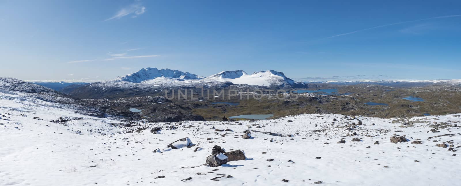 Wide Panoramic view from Krossbu on glacier Smorstabbreen, snow-capped mountains and blue lakes in Jotunheimen National Park, Western Norway.