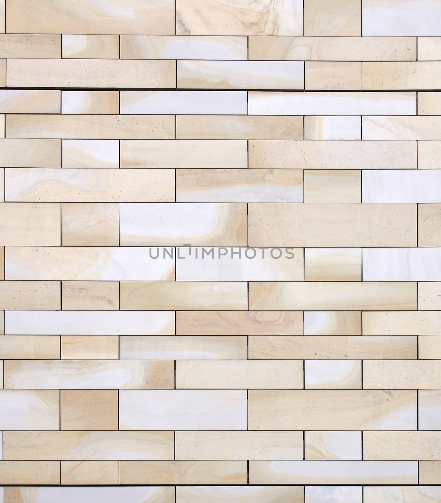 full frame image of a wall made of large flat blocks of textured yellow light brown york stone in different sized rows