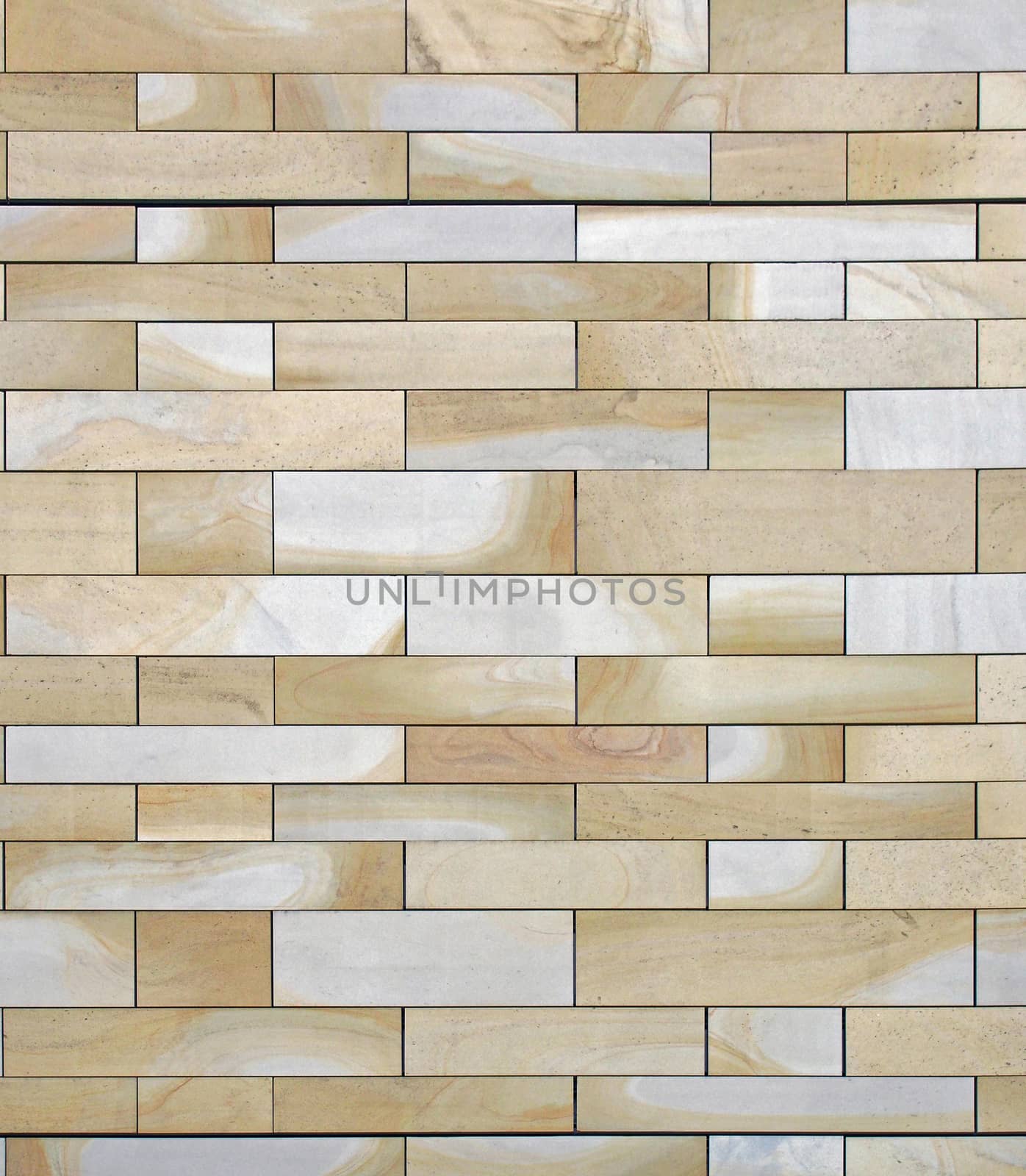 a full frame image of a wall made of large flat blocks of yellow and grey york stone with a marbled texture