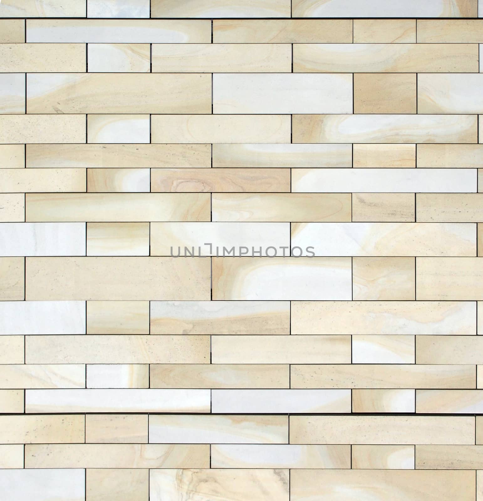 full frame image of a wall made of large flat blocks of textured yellow light brown york stone in different sized rows