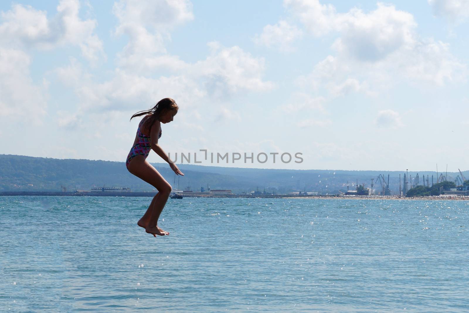 girl jumping into the sea from the pier