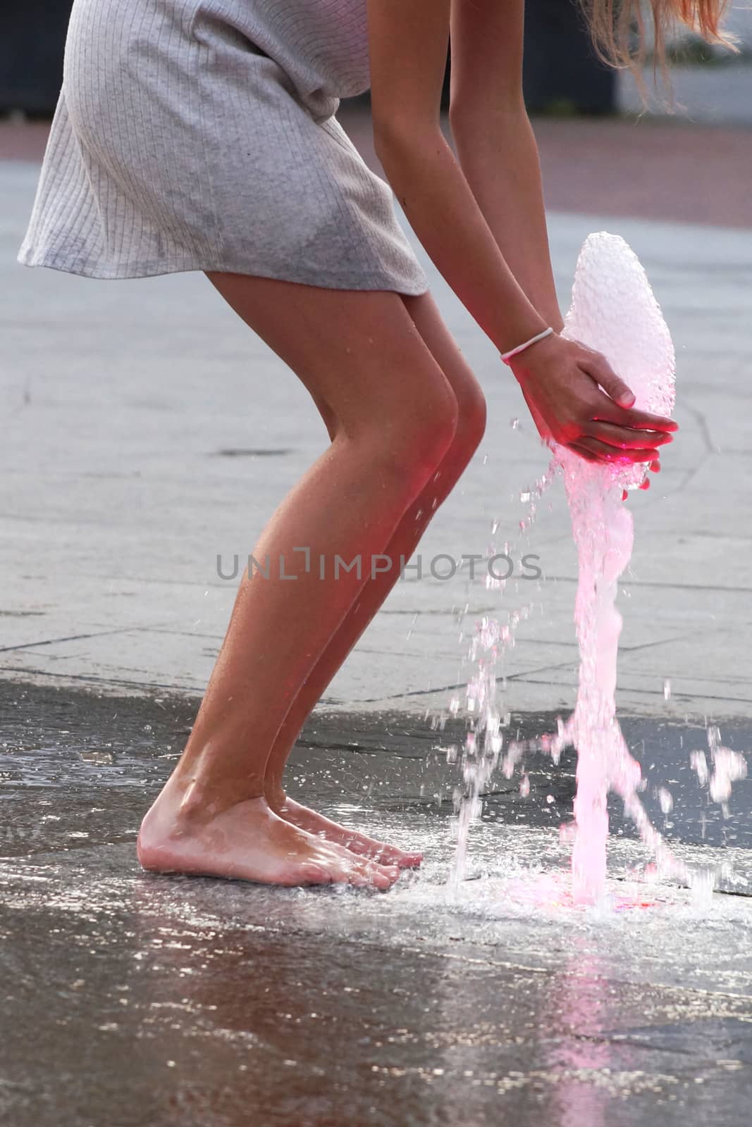 barefoot girl touching the fountain on the sidewalk