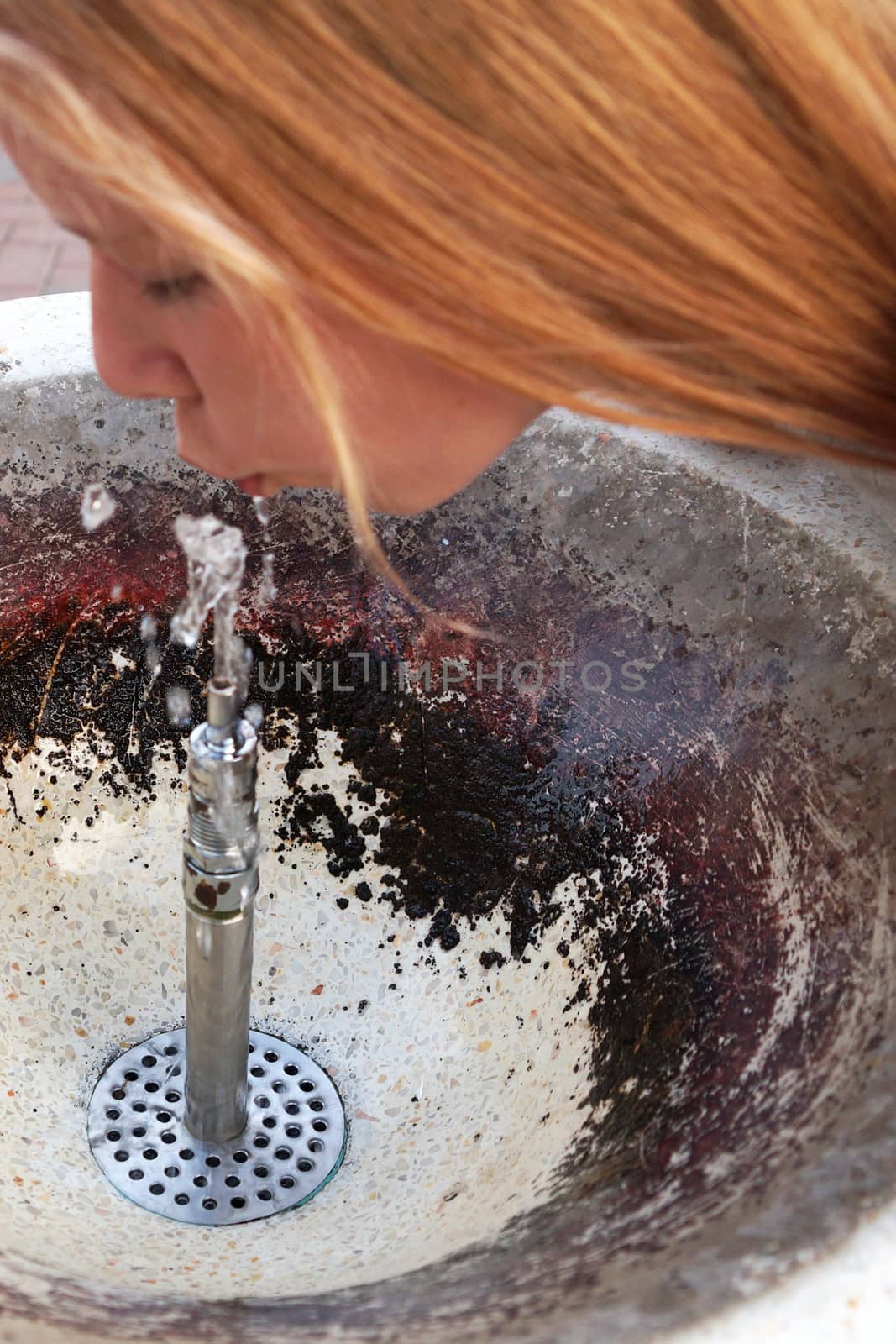 girl drinks water from a fountain close up by Annado