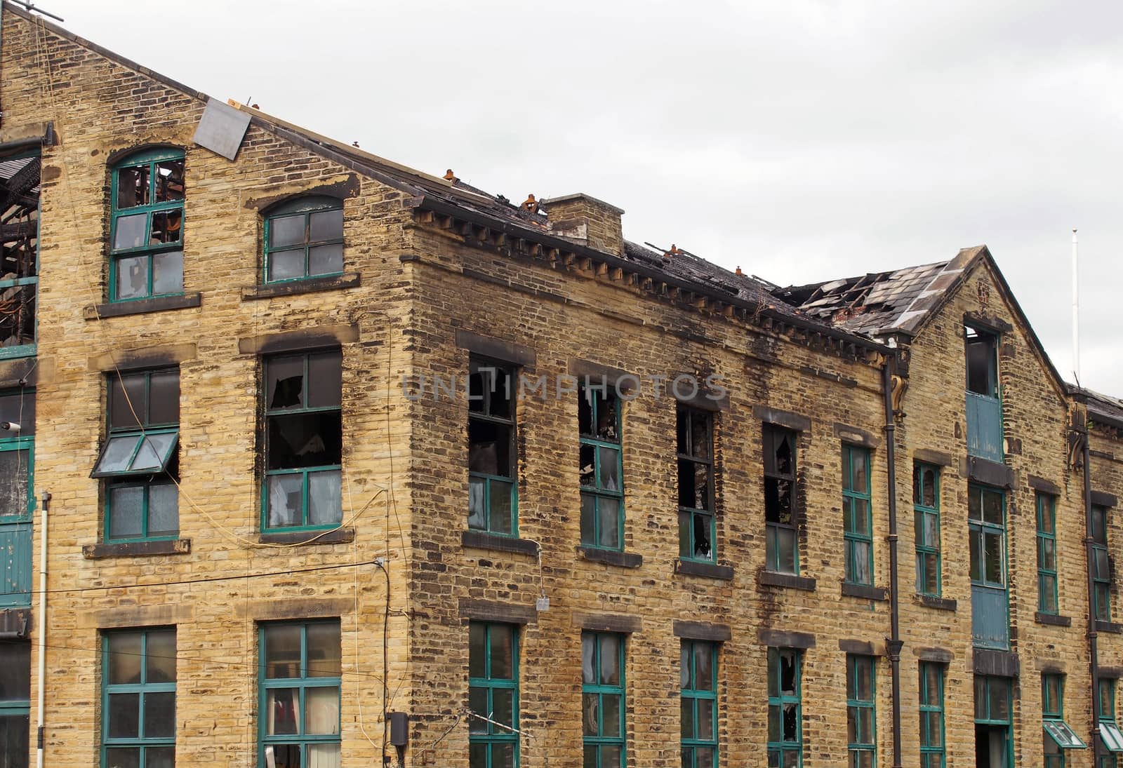 the broken roof and broken windows in a large burned out old industrial building after a fire