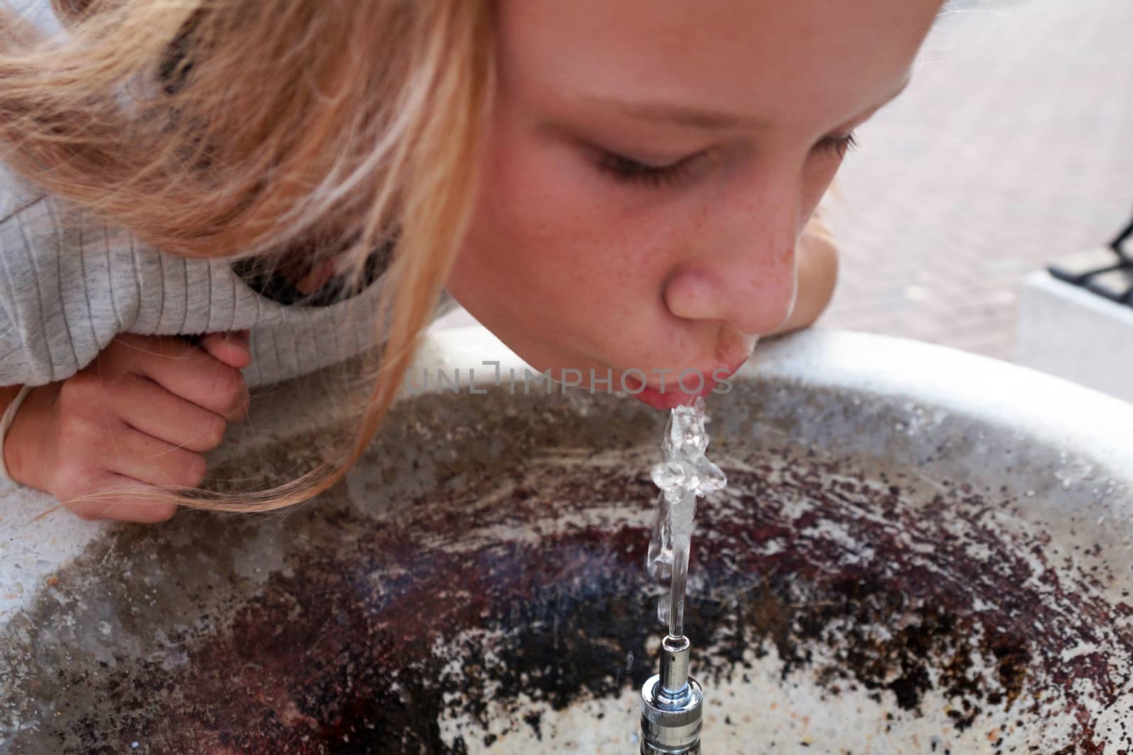 girl drinks water from a fountain close up by Annado