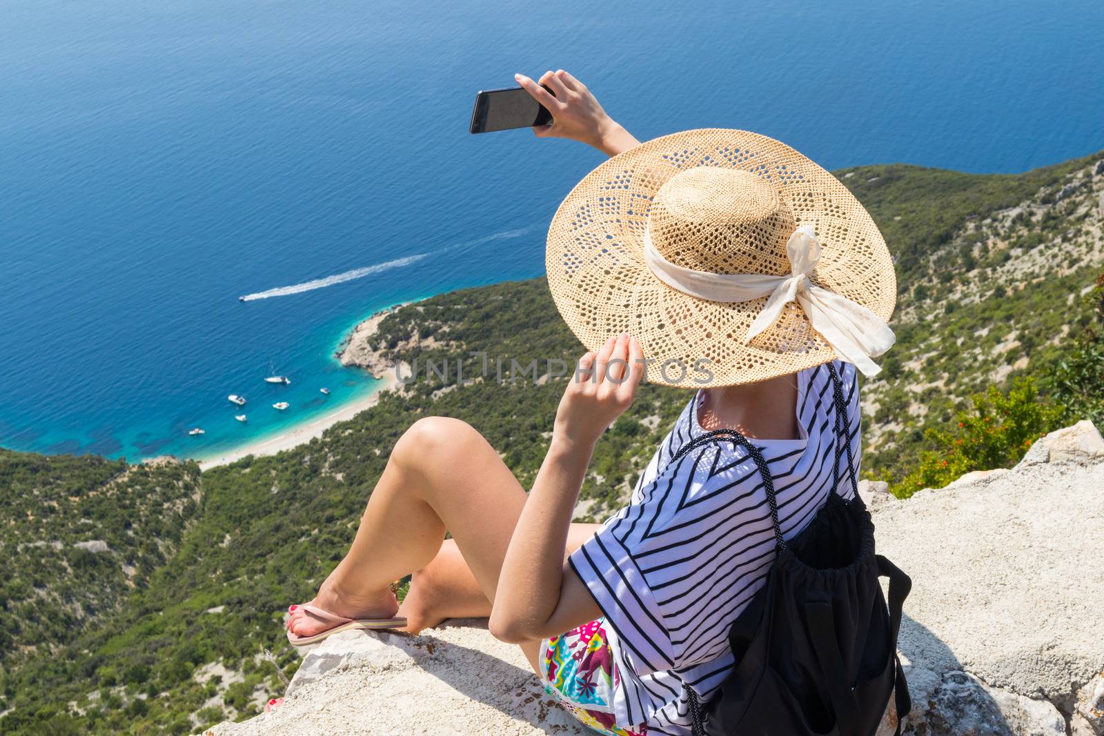 Active sporty woman on summer vacations taking selfie picture while enjoying beautiful coastal view of Cres island, Croatia from Lubenice traditional costal village.