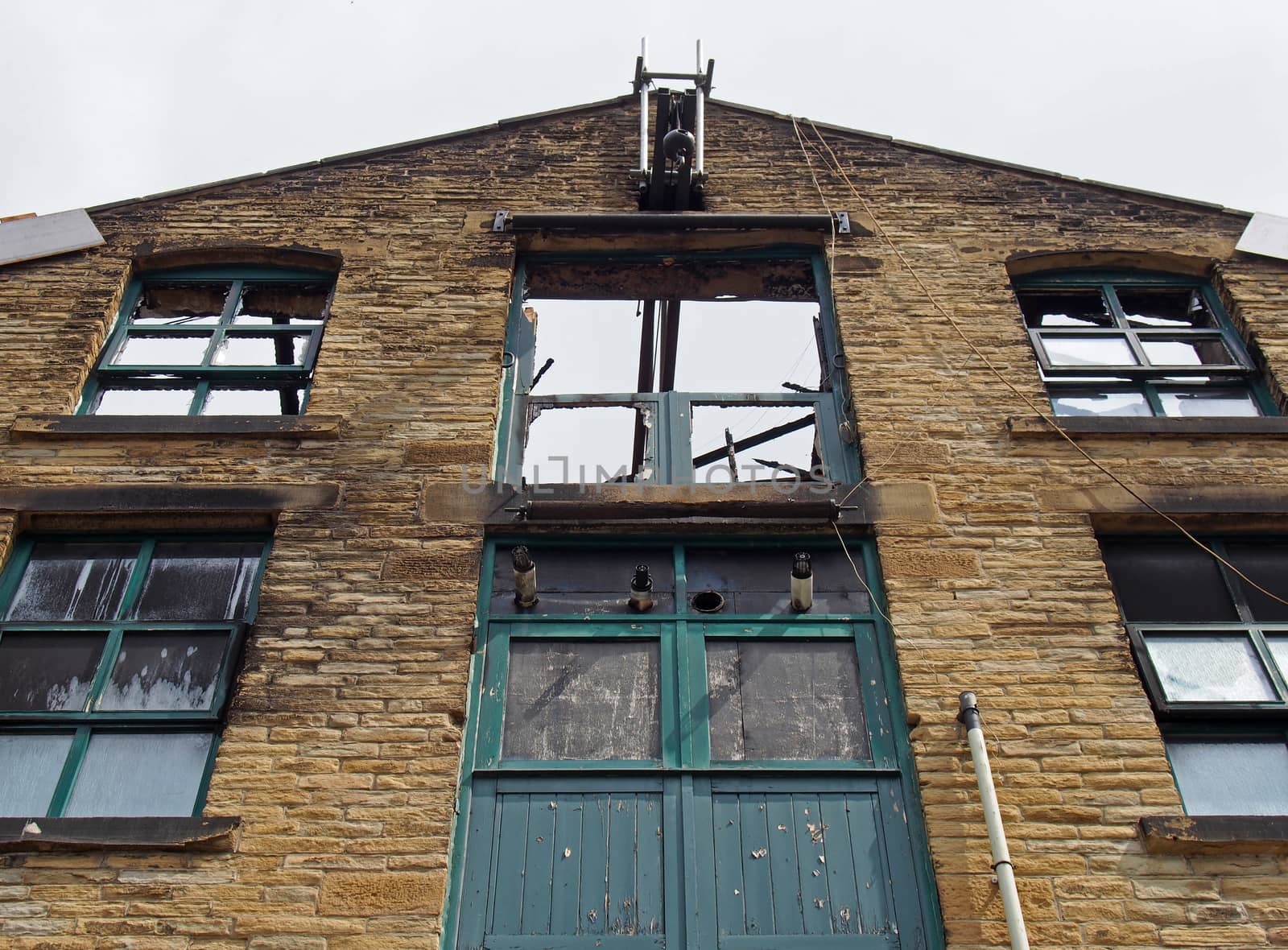 an abandoned derelict industrial warehouse building with missing roof and broken windows