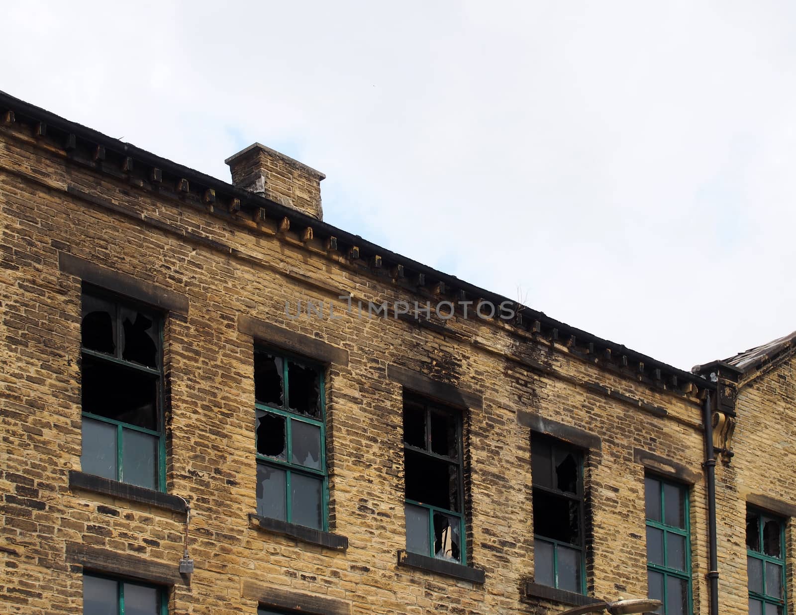 an abandoned derelict industrial warehouse building with missing roof and broken windows