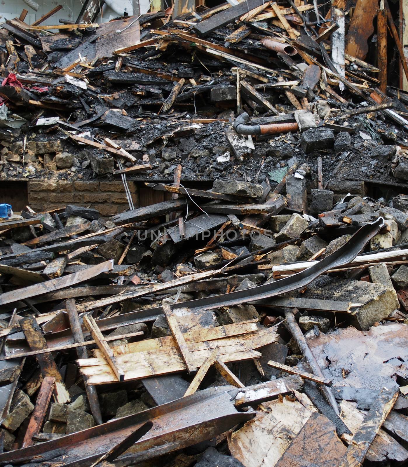 a heap of burned and scattered bricks beams and rubble after a fire in a large building
