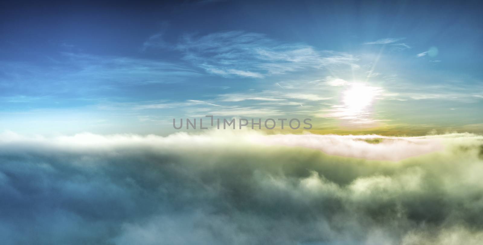 Aerial panorama photo of winter Sun before sunset above frosty subarctic clouds, very fluffy light clouds colored by sun rays and darkened from below by frosty fog and air. Northern Sweden, Lappland by skydreamliner