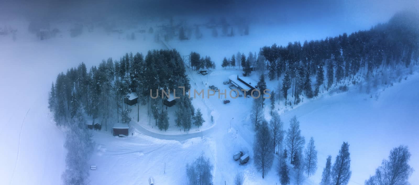 GRANO, SWEDEN FEBRUARY 08, 2020: Aerial view at bird’s nest up high in the tree canopy, houses of Grano Beckasin, tourist place at shores of beautiful Umeriver winter foggy nature, Subarctic Sweden