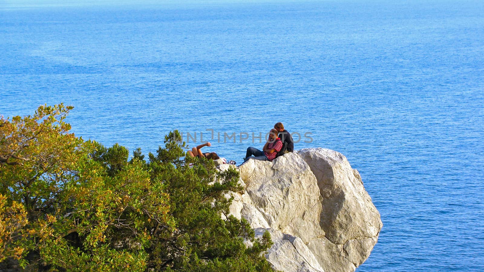 A group of people settled down to rest on a rock above the sea