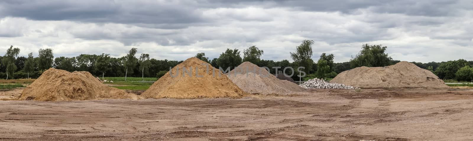 View into a gravel pit with piles of sand and tire tracks