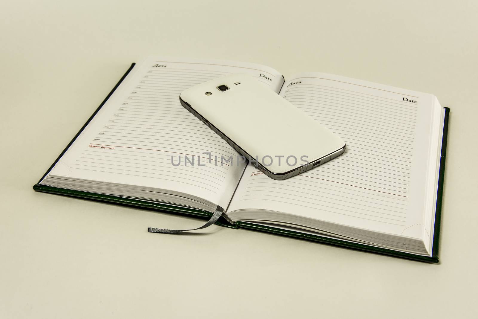 Diary on a white background and a smartphone lying on it by Grommik