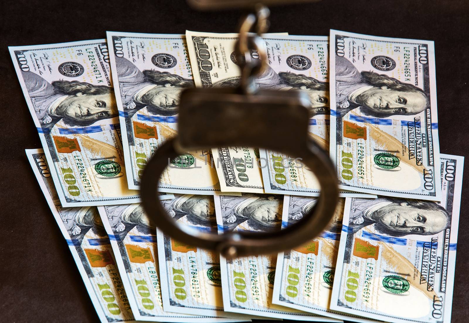 Handcuffs on one hundred banknotes of US dollars