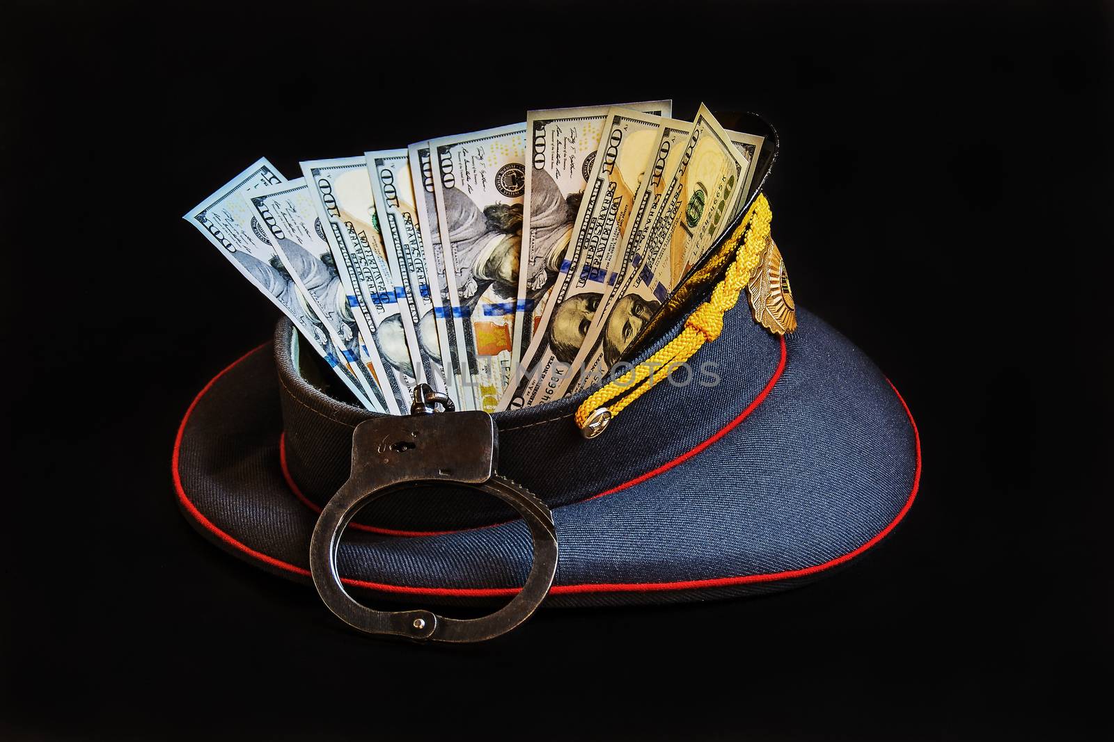 Abstract picture with the image of a police cap, handcuffs and US currency

