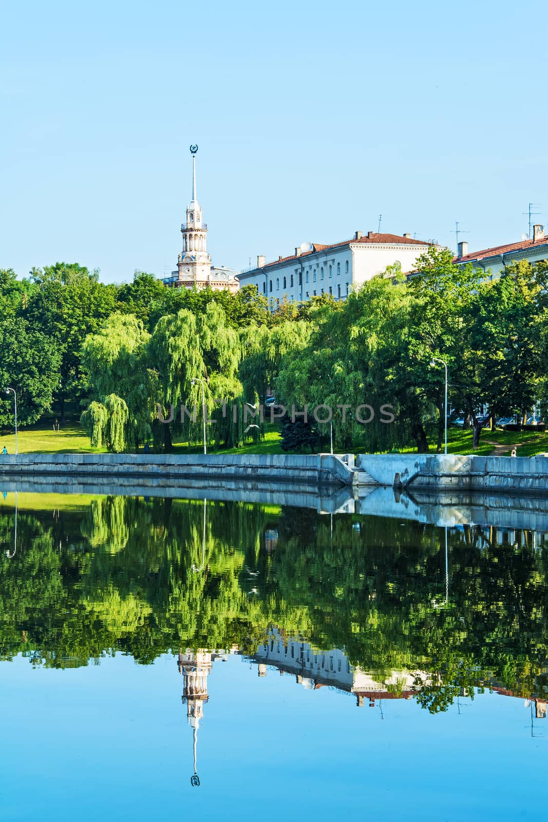 City landscape with reflection shore in the calm water of the ri by Grommik