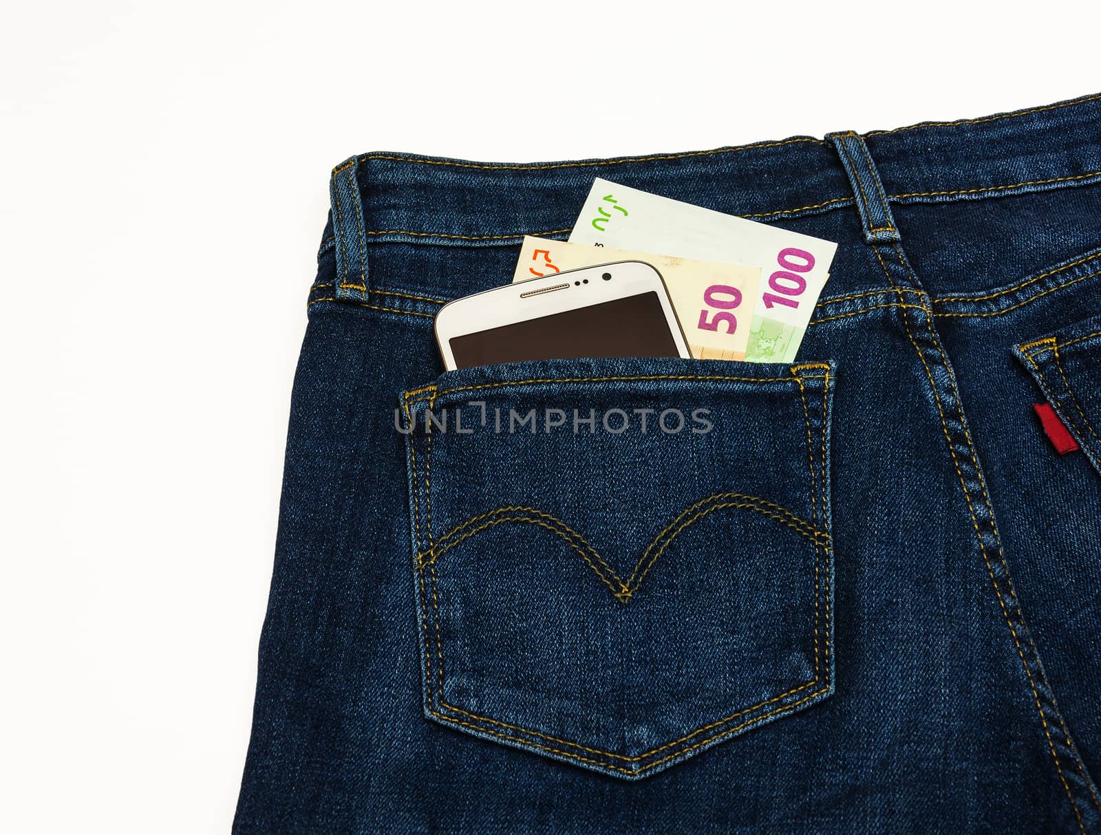 Trousers sewn from a blue denim lie on a white surface. In the back pocket of his pants is smart and banknotes.

