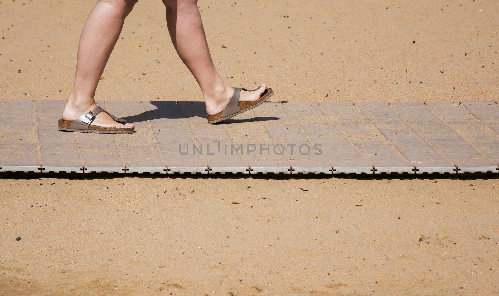 Feet in the summer slates on the beach sand track by Grommik