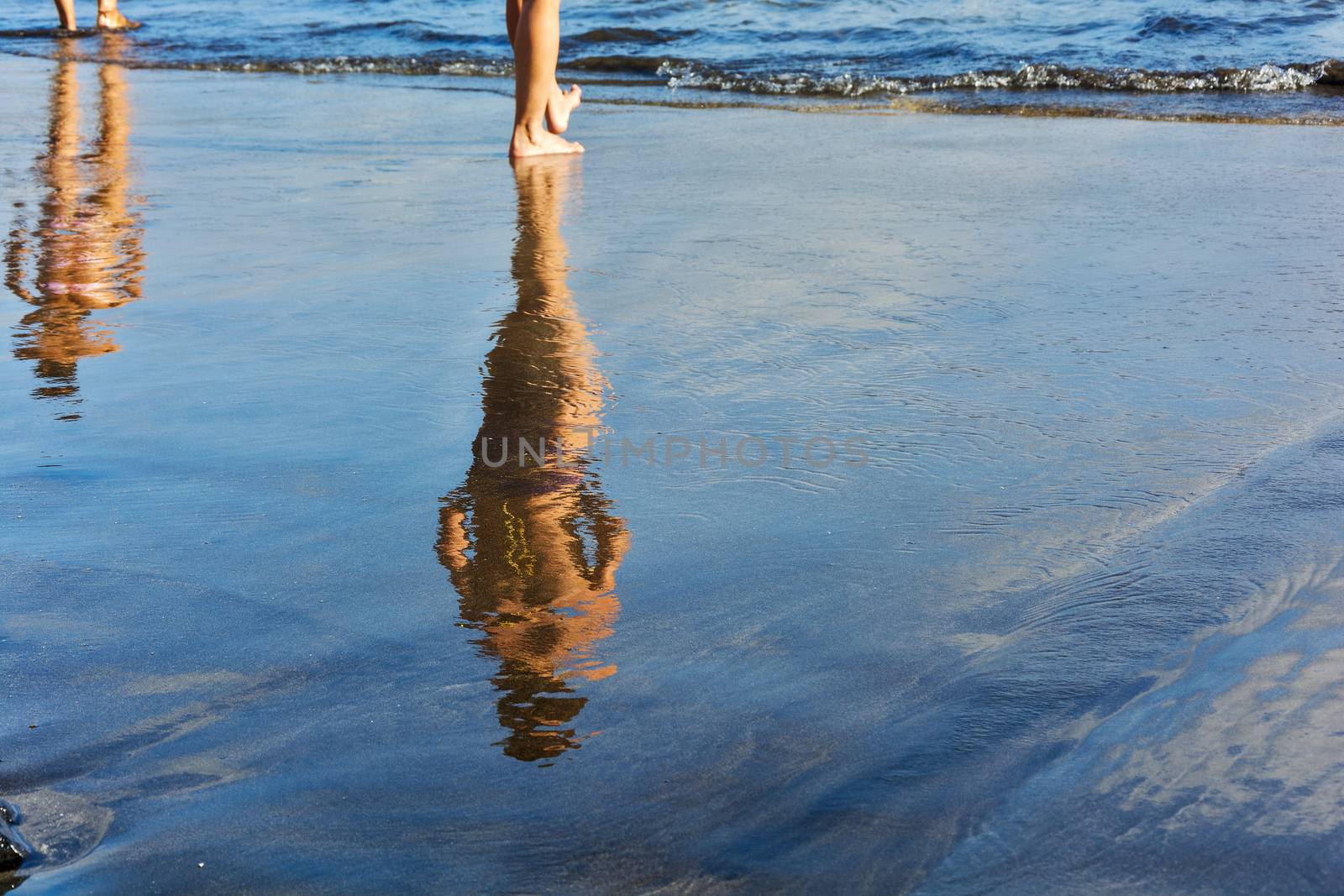 Two female figures are reflected in the wet sand prebrezhnogo