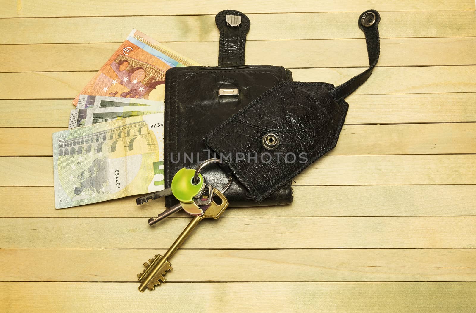 Leather purse with keys lie on a wooden surface by Grommik