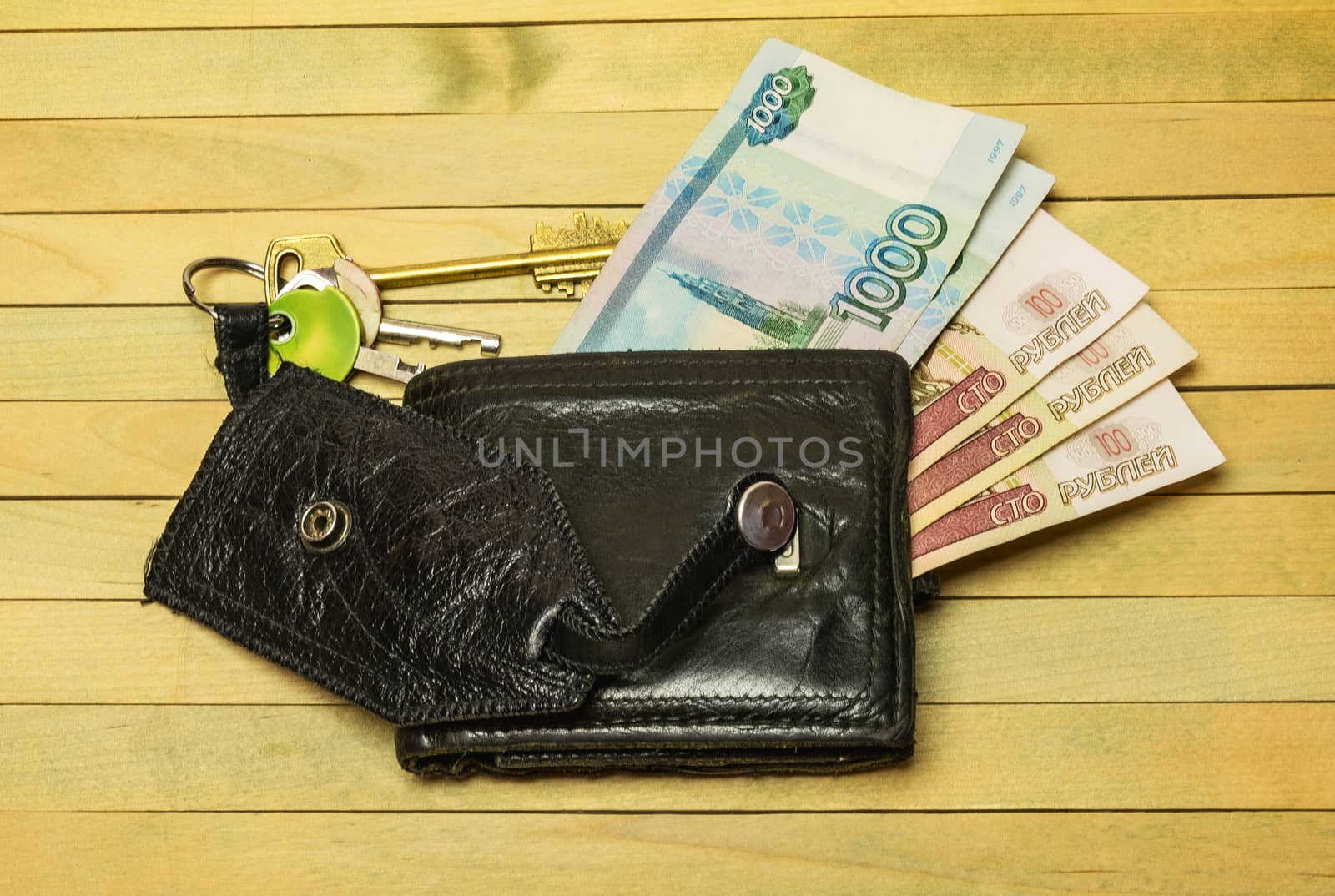 Leather purse and keys lie on a wooden surface by Grommik