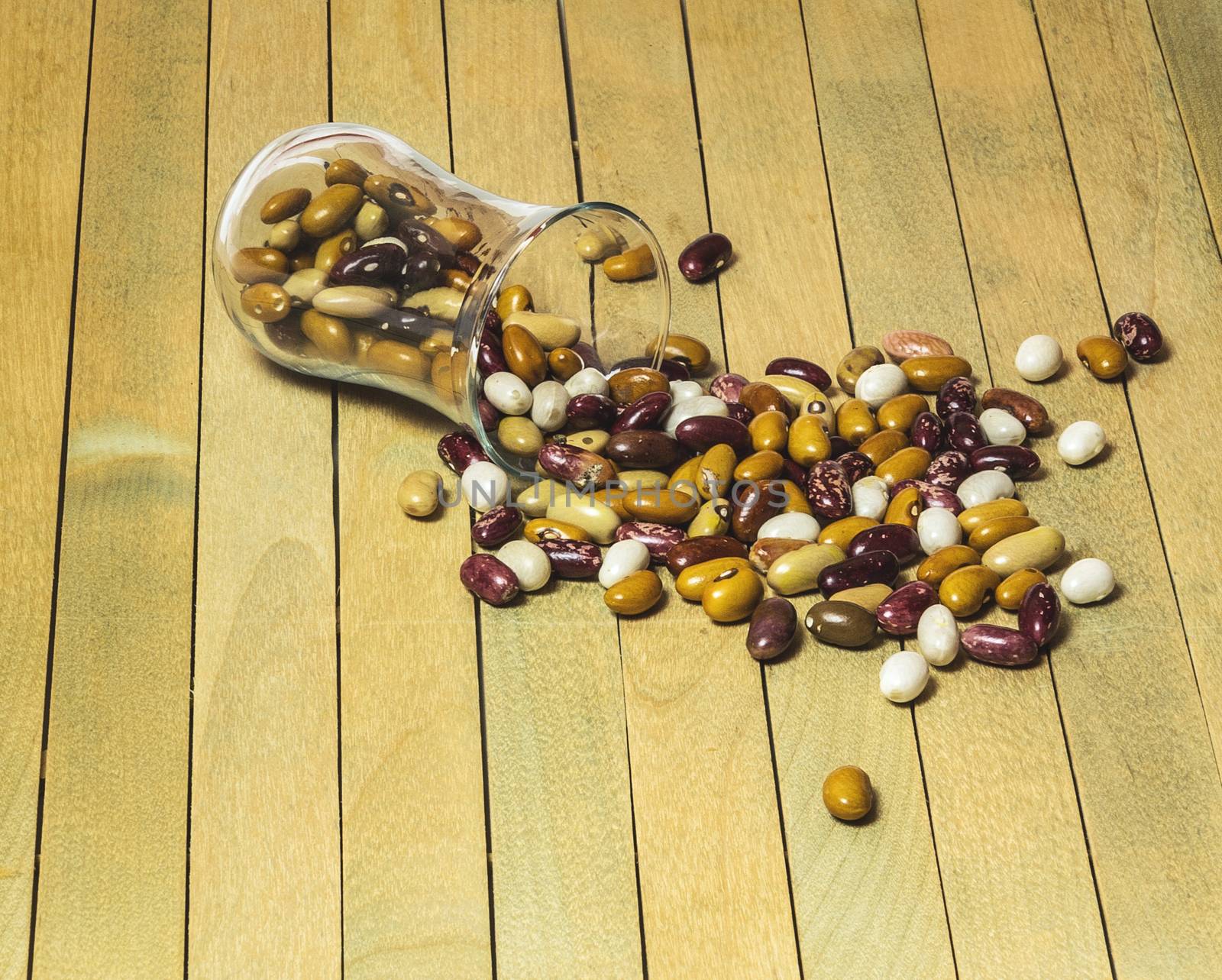 Beans beans spilled from a glass container on a wooden surface by Grommik