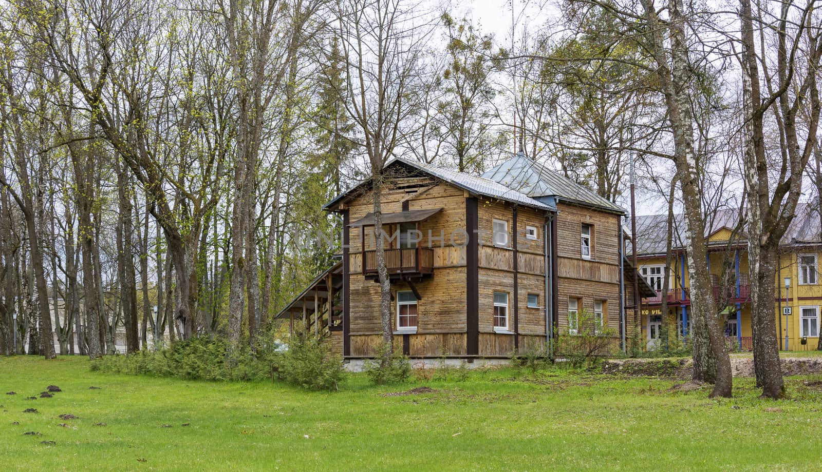 Two-storey wooden house built in the trees near the green lawn by Grommik