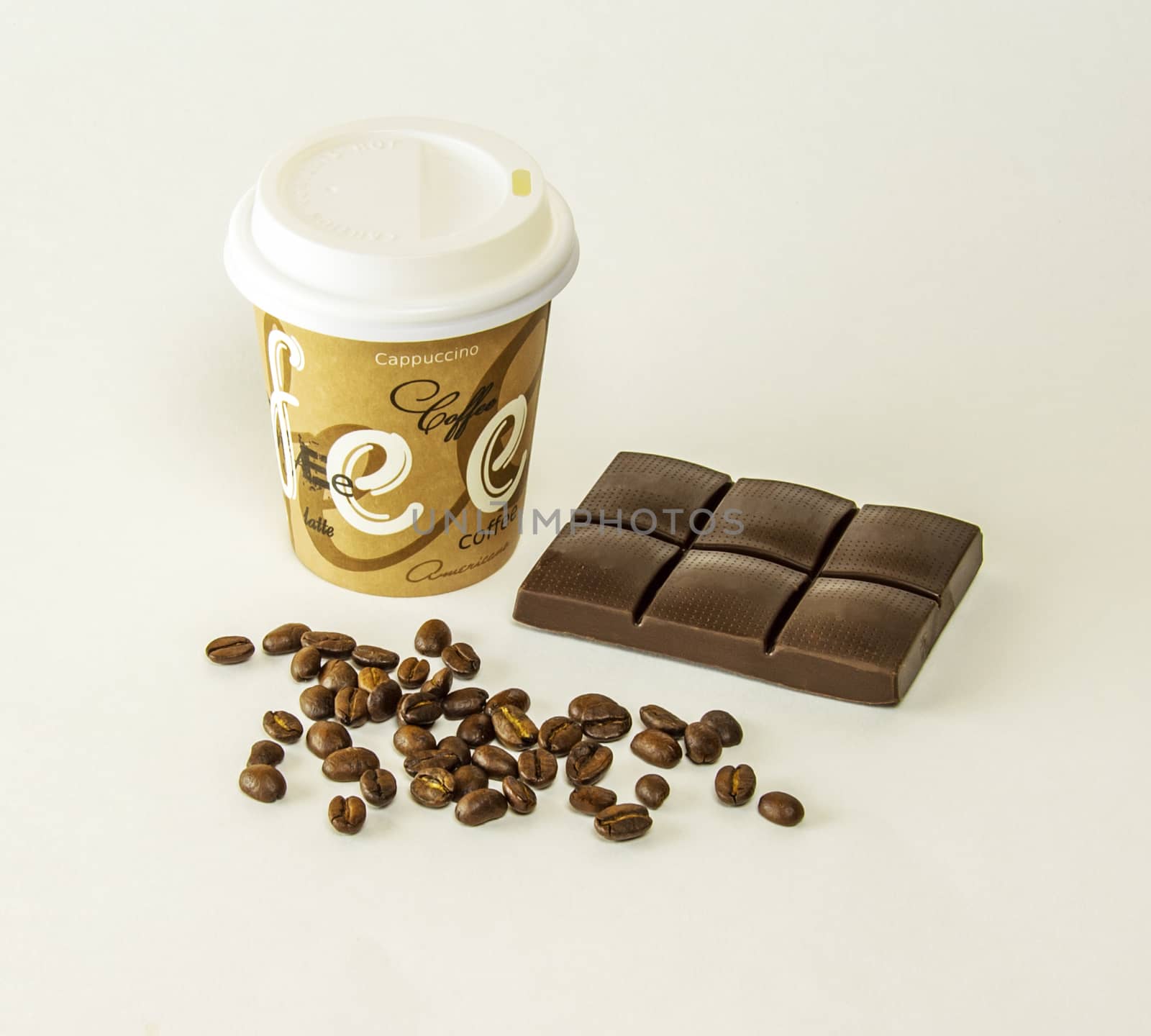Paper cup with tiles of dark chocolate and coffee beans scattere by Grommik
